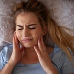 woman in bed grinding teeth