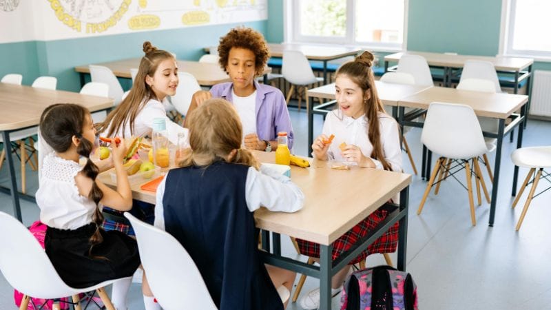 Group of children eating a healthy lunch around a table