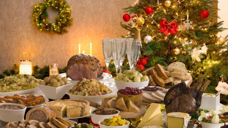 A selection of good and bad festive foods for dental health laid out on a table with a Christmas tree in the background