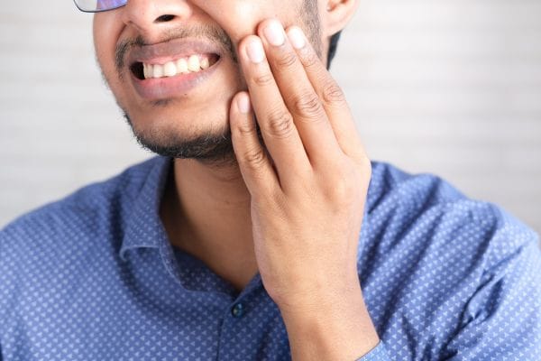 Man hoding the side of his face due to sensitive teeth