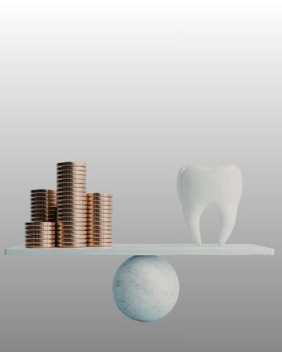 scales with coins piled up on one side and a tooth on the other signing the question how much do dental implants cost in the UK